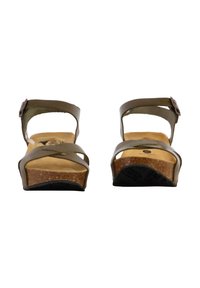 Sandales en cuir marron avec une semelle en liège, dotées de brides croisées et d'une sangle de cheville réglable. Talon plat, conçues pour le confort.