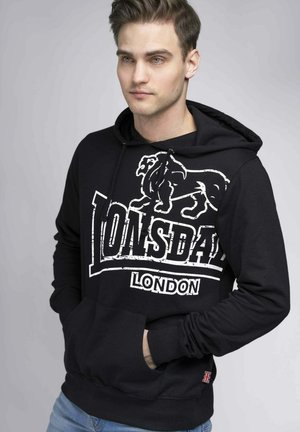 Sudadera negra con gráfico de un león y el texto "Lonsdale London". Fabricada en tejido suave, con un bolsillo tipo canguro y puños acanalados.