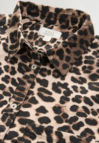 Leopardenmuster-Hemd aus Leinen, mit kragen, Knopfverschluss und Farbtönen von Braun, Schwarz und Beige in einer weichen Textur.