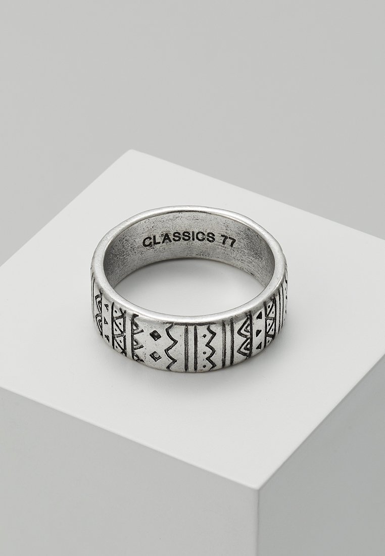 Sølvring med geometriske mønstre graverte rundt ringen, med en teksturert overflate og en innvendig gravering av "CLASSICS 77."