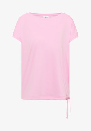 Jasnoróżowa koszulka z krótkim rękawem, okrągłym dekoltem i regulowanym wiązaniem po prawej dolnej stronie.