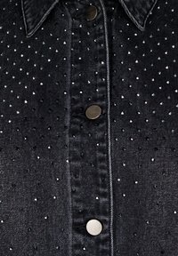 Černá denimová košile s rozloženým límcem, zdobená kovovými cvočky a knoflíkovým zapínáním. Měkká struktura s pevným designem.