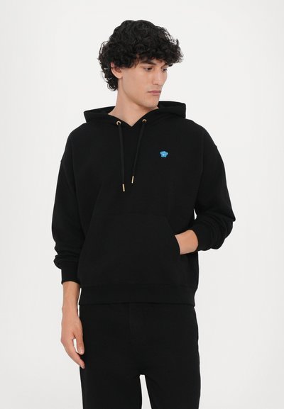 Felpa nera con cappuccio in tessuto morbido, caratterizzata da una tasca frontale, un cappuccio con cordini e un piccolo logo blu sul petto.