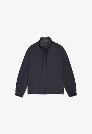 Granatowa kurtka na zamek z wysokim kołnierzem, elastycznymi mankietami i bocznymi kieszeniami na zamek, rozłożona na białym tle.