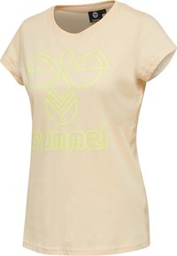 Camiseta de algodón color durazno con mangas cortas, que presenta un gran diseño de logo reflectante amarillo en la parte frontal y un escote en forma de barco.