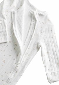 Body de manga larga blanco, hecho de algodón, con cierre de cremallera, puños acanalados y un estampado de estrellas y lunas en marrón claro.