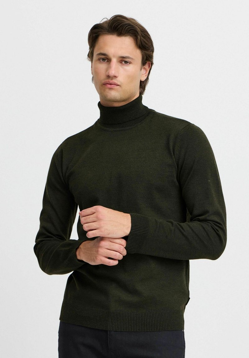 Pull à col roulé vert foncé avec manches longues et poignets côtelés. Fabriqué dans un tissu doux, il présente une coupe décontractée et une texture subtile.