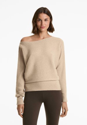 Beige ribbeltrui met een off-shoulder ontwerp, lange mouwen en een relaxte pasvorm. Zachte textuur met een zoom die op de taille valt.