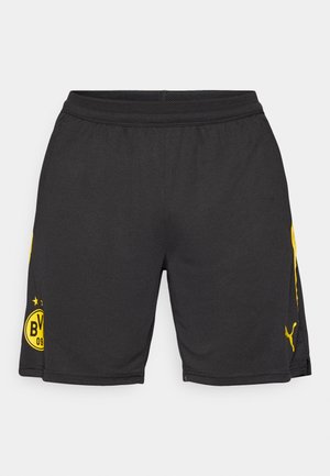 Shorts de sport noirs avec des accents jaunes, présentant un logo sur le côté gauche et une taille en maille pour la respirabilité. Fabriqués en matériau léger.