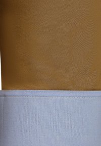 Bruin en lichtblauwe stof met een gestructureerd ontwerp. Het bovenste gedeelte is een gladde bruin terwijl het onderste gedeelte een geweven textuur heeft.