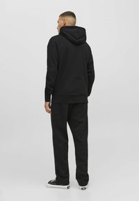 Zwart hoodie met een trekkoordcapuchon, gecombineerd met bijpassende joggingbroek. Glad oppervlak, relaxte pasvorm, afgewerkt met een geribde zoom en manchetten.
