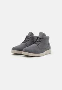 Stivaletti alla caviglia in suede grigio con una tomaia liscia, punta arrotondata e una suola in gomma leggera e testurizzata; presentano lacci coordinati e un sottile dettaglio del logo.
