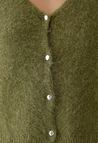 Olivgrüner, flauschiger Strickcardigan mit V-Ausschnitt und silbernen Knöpfen auf der Vorderseite, der aus einem weichen, strukturierten Stoff besteht.