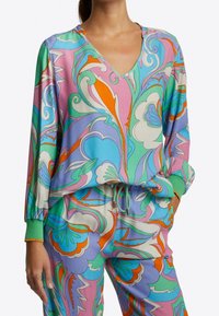 Färggård loungewear-set med ett livfullt blommönster. V-ringad topp och byxor med dragsko erbjuder pastellfärger, gröna muddar och en avspänd passform.
