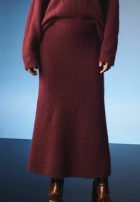 Burgundská dlouhá pletená sukně z jemné texturované látky, spárovaná s odpovídajícím oversized svetrem, který má žebrované manžety a dolní lem.