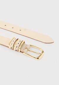 Beige nahkainen vyö, jossa on kullanvärinen metallisolki, kolme koristeellista nauhaa pyöreillä leikkauksilla ja tasaisesti sijoitetut reiät koon säätöä varten.