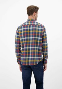 Geruit overhemd van katoenflanel met rode, blauwe, gele en witte vierkanten, lange mouwen en een gebogen zoom. Met knoopsluiting bij de manchetten.