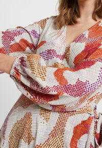 Robe portefeuille à manches longues en tissu léger, ornée d'un motif abstrait multicolore avec des détails orange, violet et doré. Poignets élastiques.