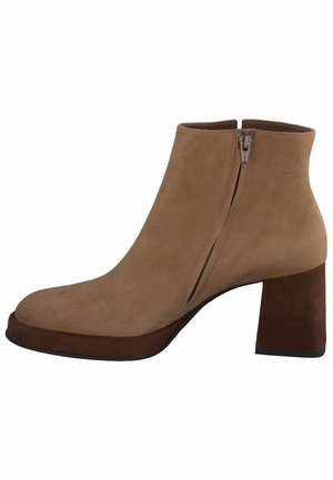 Bottes ankle en cuir suédé beige avec un bout arrondi, une fermeture éclair sur le côté et un large talon carré. Texture douce avec un accent de talon marron contrastant.