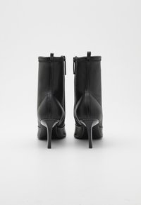 Schwarze Leder-Stiefeletten mit glatter Textur, enger Silhouette, hohen Stiletto-Absätzen und einem Reißverschluss auf der Rückseite.