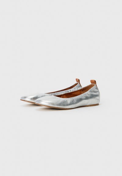 Zilveren platte schoenen van metallic leer met een ronde neus en een lichte elastische afwerking bij de opening. Bruine leren accenten op de hak.