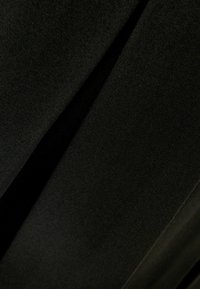 Černá tkanina s hladkým, matným povrchem a jemným leskem. Materiál má měkký spad a je složený, což ukazuje na hloubku.