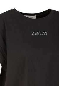Camiseta negra de algodón con cuello redondo. Presenta un sutil logo plateado "REPLAY" bordado en el frente. Textura suave.
