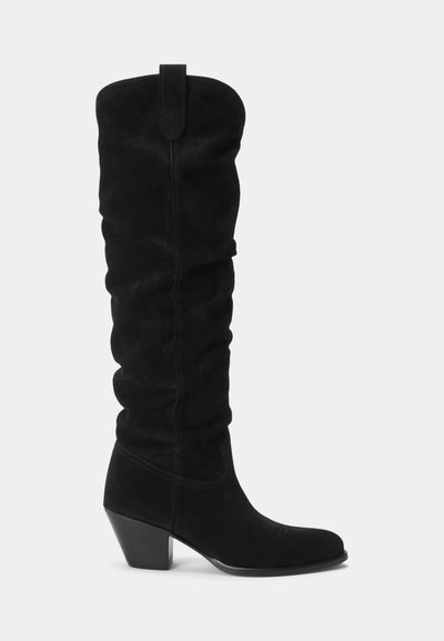 Μαύρο σουέντ μποτάκι μέχρι το γόνατο με χαλαρή σχεδίαση, μυτερή μύτη και ψηλό τακούνι. Διαθέτει θηλιά στην κορυφή για εύκολη εφαρμογή.