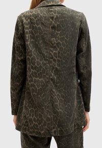 Leopardmönstrad jacka i olivgrön tyg, med skräddarsydd passform, knappkrage och synliga sömnadsdetaljer på baksidan.