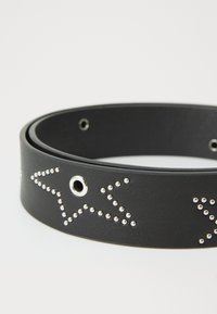 Cinturón de cuero negro con acentos tachonados en forma de estrella y múltiples orificios para ajuste de tamaño. Textura suave con detalles metálicos brillantes.