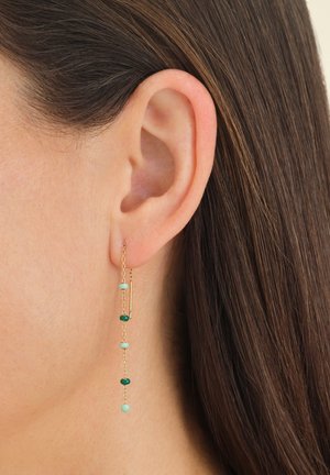 Boucles d'oreilles en chaîne dorée ornées d'un agencement de perles vertes et aqua de différentes formes, avec un design linéaire qui cascade sous le lobe de l'oreille.
