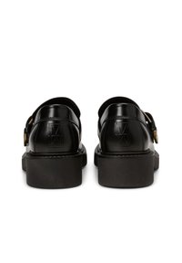 Chaussures en cuir noir avec une finition lisse, deux sangles ajustables et une semelle épaisse noire. Logo notable embossé sur le talon.