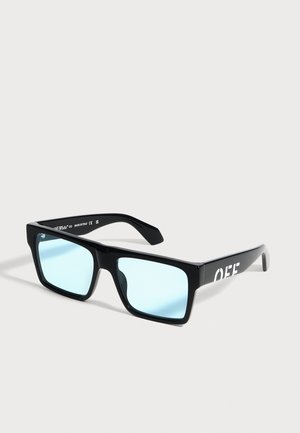 Lunettes de soleil rectangulaires noires avec verres bleu clair et texte blanc « OFF » sur les branches, exposées sur un fond clair uni.