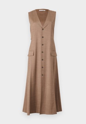 Hihaton ruskea midi-mekko, jossa etukappaleen napit ja läppätaskut, yhdistettynä mustiin korkokenkäsandaaleihin ja pieneen tummanväriseen käsilaukkuun.