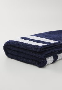 Serviette bleu marine avec des rayures blanches, fabriquée en tissu éponge doux, soigneusement pliée pour mettre en valeur la texture et le contraste des couleurs.