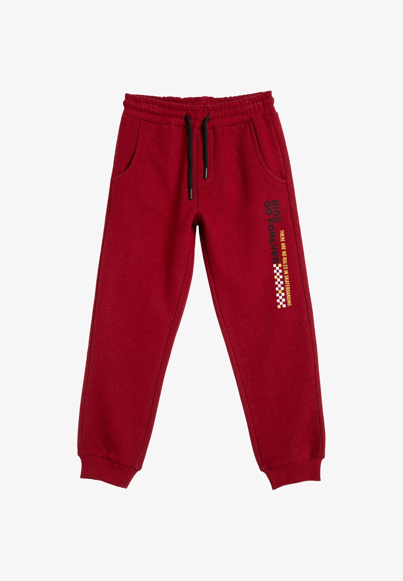 Røde joggingbukser med sort snor, sidelommer, elastiske manchetter og sort samt gul tekst med et ternet mønster på højre lår.