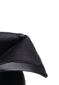 Juodas odinis skrybėlė su minkštu, pūkuotu viršumi, plačia skrybėlių juosta ir struktūruotu dizainu, pabrėžiant tekstūrą ir kontrastą tarp medžiagų.