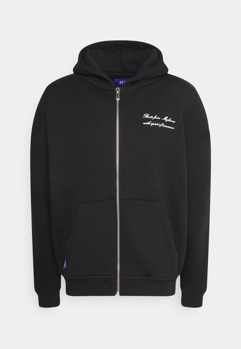 Zwarte hoodie met ritssluiting, voorzakken en witte tekst op de linkerborst waarop staat: "Roots from Mykonos with spirit of tomorrow."