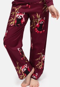 Bordeauxkleurige pyjamabroek met een patroon van rode panda's en bamboe. Gemaakt van zachte stof met een relaxte pasvorm en rechte pijpen.