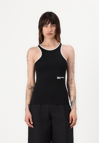 Top negro sin mangas con ribete blanco, que presenta un diseño ajustado y un logo en la parte inferior del frente. Tejido suave con un ligero brillo.