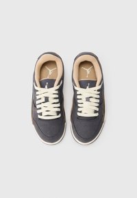 Un par de zapatillas de ante gris oscuro con cordones blancos y forro interior beige, vistas desde arriba sobre un fondo claro y liso.
