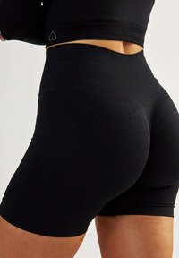 Czarne, elastyczne spodenki sportowe z wysokim stanem. Teksturowany materiał poprawia dopasowanie, z subtelnym logo serca na pasku.