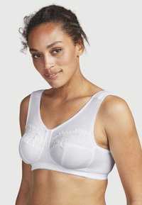 Valkoinen rintaliivi, jossa on kukkakirjontaa kuppeissa, sileää satiinimaista materiaalia, leveät olkaimet ja V-muotoinen kaula-aukko.