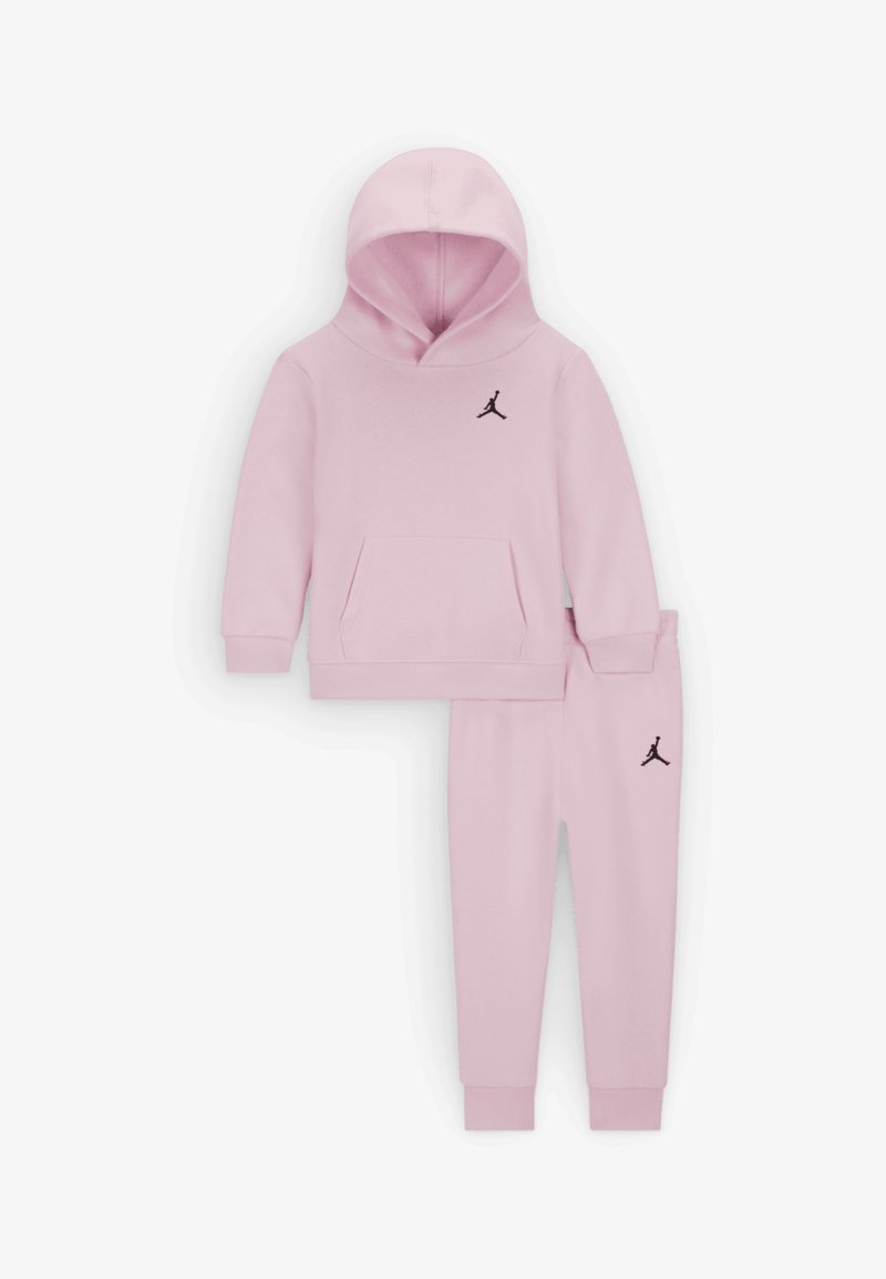 Light pink hoodie and sweatpants set, featuring a front pocket, ribbed cuffs, and a black logo on the chest and thigh. Soft fabric texture.
