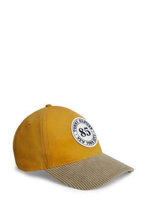 Casquette de baseball jaune avec une visière beige côtelée et un écusson rond portant la mention "Tommy Hilfiger 85 New York City" à l’avant.