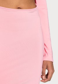 Blusa rosa de mangas longas com um design ajustado e uma textura suave e macia. Apresenta um decote arredondado e mangas justas.