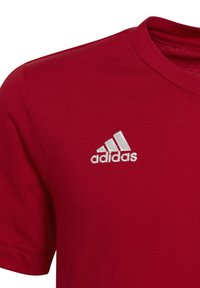 T-shirt in cotone rosso con scollo rotondo e maniche corte. Logo Adidas ricamato bianco ben visibile sulla parte sinistra del petto.