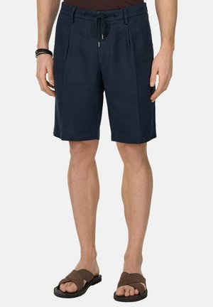 Pantaloncini da uomo blu navy fino al ginocchio con passanti per cintura e coulisse, indossati con sandali slip-on marroni, mostrati dalla vita ai piedi.
