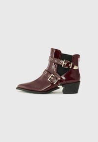 Bottes de cheville en cuir verni bordeaux avec un bout pointu, deux courroies ajustables, boucles en argent et un petit talon carré.