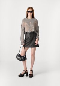 Gray knitted cropped sweater with cutouts, black leather mini skirt, black platform sandals, and a black shoulder bag with studded accents.